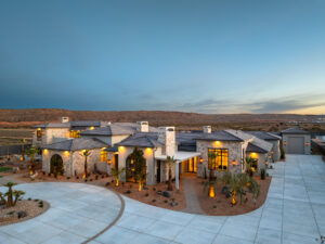 Custom luxury home exterior in St. George, Utah, featuring stone façade, landscaped yard, and sunset backdrop, showcasing RL Wyman's design and craftsmanship.