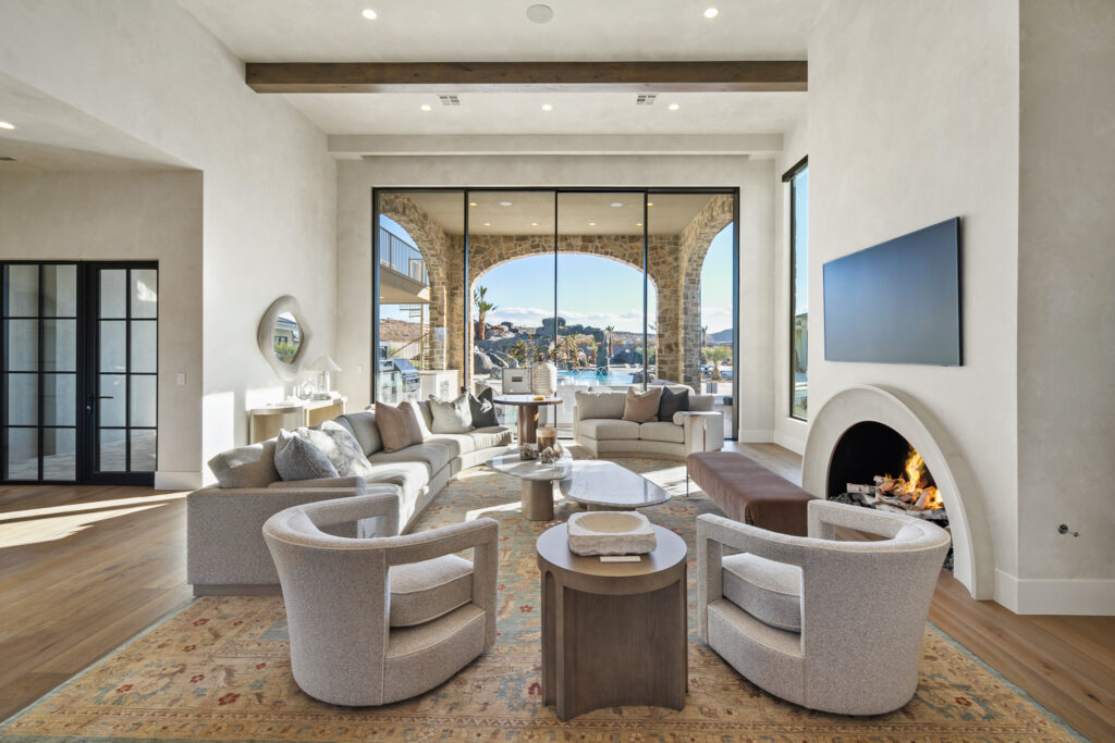 Luxurious living room featuring modern furniture, a cozy fireplace, and large windows showcasing scenic views, highlighting custom home design in Hurricane, Utah.