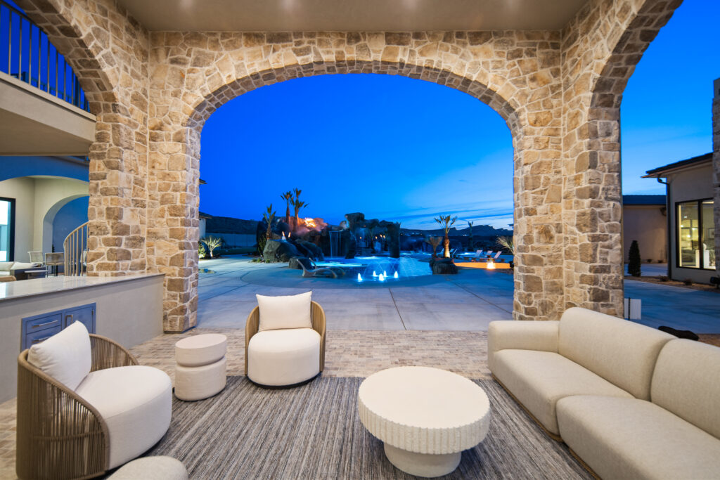 All-inclusive outdoor patio with stone arches, modern furniture, and a pool view, showcasing a luxurious living space in Toquerville, Utah.