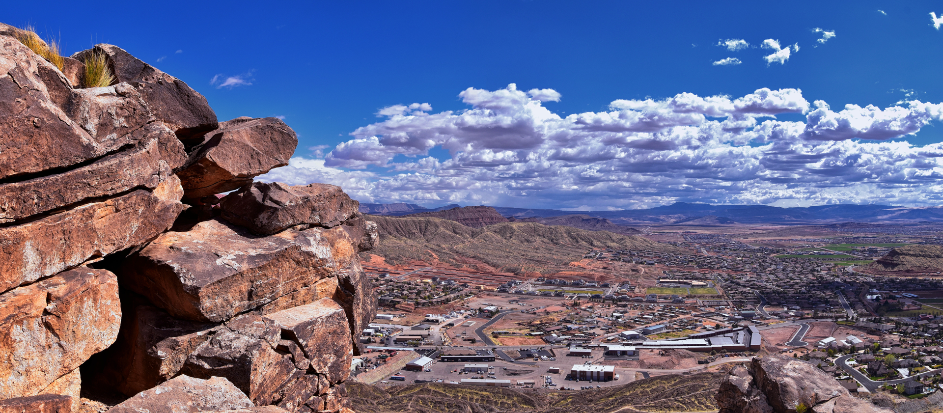 Panoramic view of Washington, Utah, showcasing desert landscapes, residential areas, and distant mountains under a blue sky with clouds, emphasizing the region's natural beauty and potential for custom home building.
